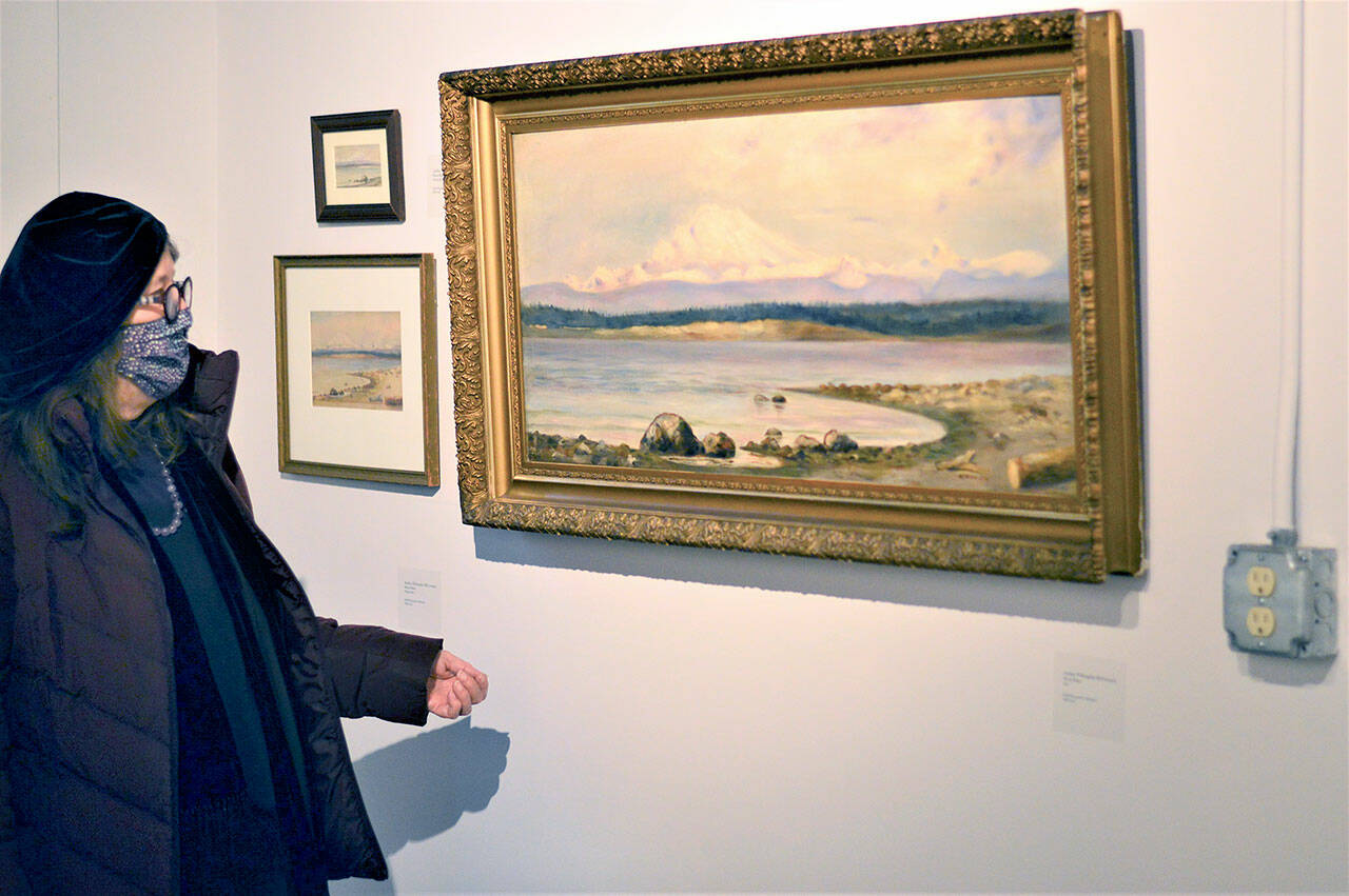 Jenny Westdal, Jefferson County Historical Society board president, admires one of Adeline Willoughby McCormack’s paintings in the “Women Outdoors” show at the Jefferson Museum of Art & History. (Diane Urbani de la Paz/Peninsula Daily News)