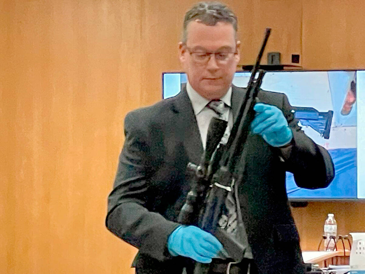 Detective Sgt. Eric Munger of the Clallam County Sheriff’s Office prepares to show a semi-automatic rifle presented in the triple-murder trial of Dennis Marvin Bauer. (Paul Gottlieb/Peninsula Daily News)