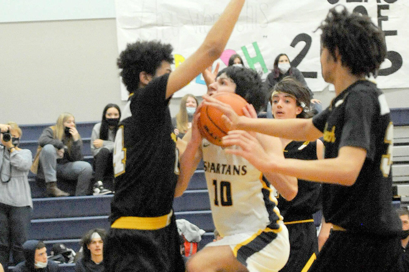 Lonnie Archibald/for Peninsula Daily News
Forks' Dylan Micheau drives the lane against North Beach's 6-foot-7 Tre' Vaughn Greene during the Spartans' home opener Wednesday.