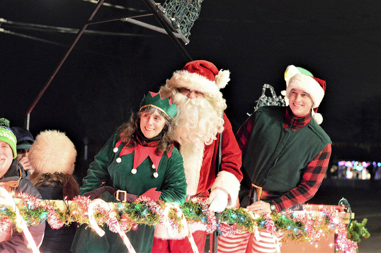 Santa Claus, flanked by elf-firefighters Tammy Ridgway and Michael Archuleta, is traveling around Port Townsend and Port Hadlock this week, handing out candy canes and stuffed toys from East Jefferson Fire & Rescue battalion chief Justin Clouse’s heavily decorated truck. (Diane Urbani de la Paz/Peninsula Daily News)