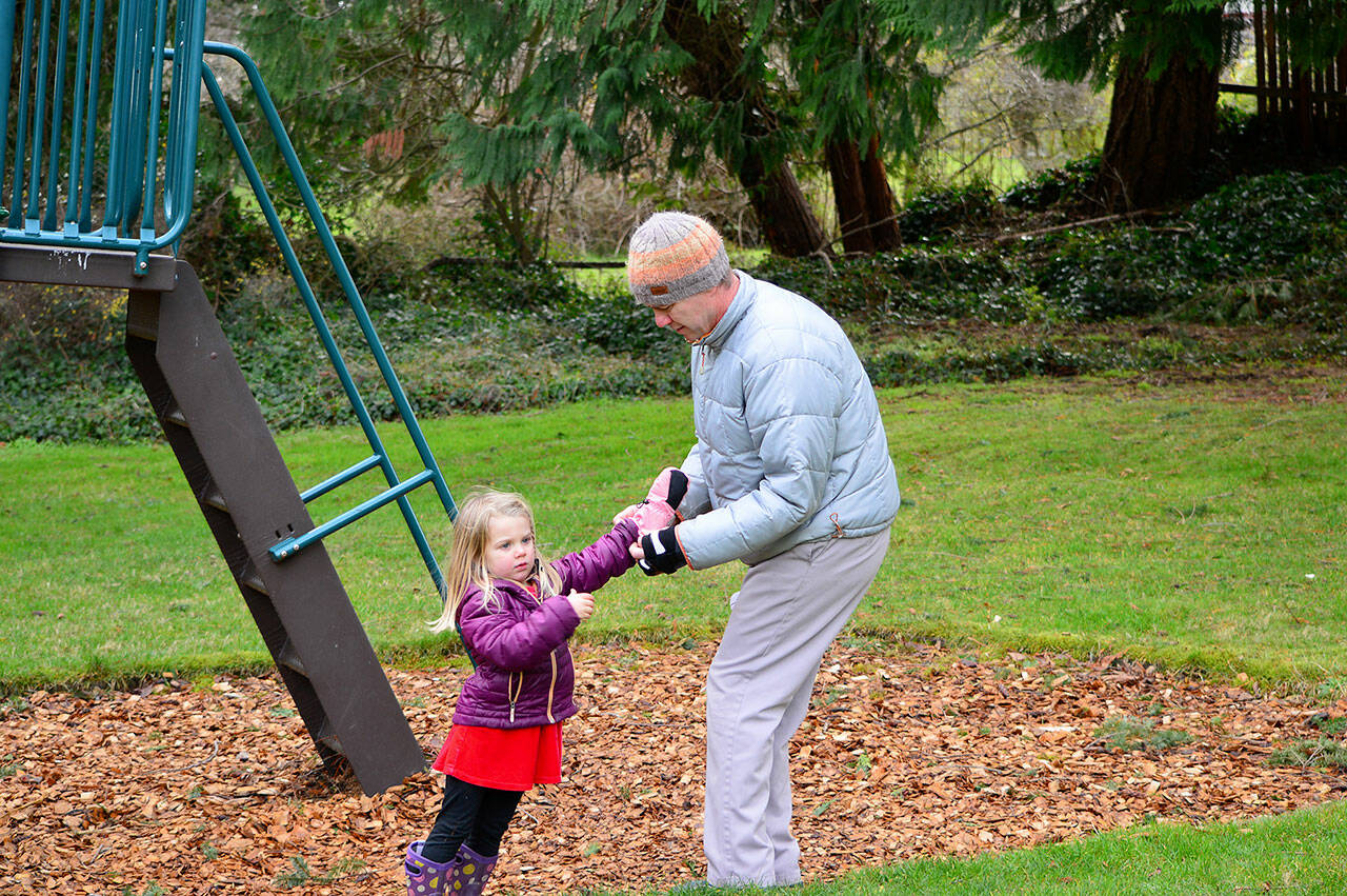 Mark Senffner of Portland, Ore., helps daughter Fionn, 3 ½, with her mittens during a Christmas Eve visit to Chetzemoka Park in Port Townsend. (Diane Urbani de la Paz/Peninsula Daily News)