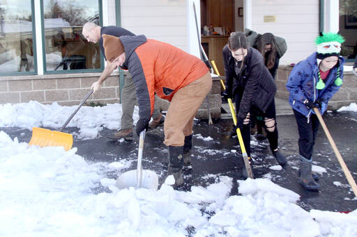 From left to right, John Glass, Scott VanDyken, Rileigh VanDyken, 17, and Isaak VanDyken, 10, scrape and shovel snow and ice away from the VanDyken Family Dentistry building in the 600 block of east Eighth Street in Port Angeles. A total of nine people volunteered to clear the sidewalks as the holiday break came to an end. (Dave Logan/for Peninsula Daily News)