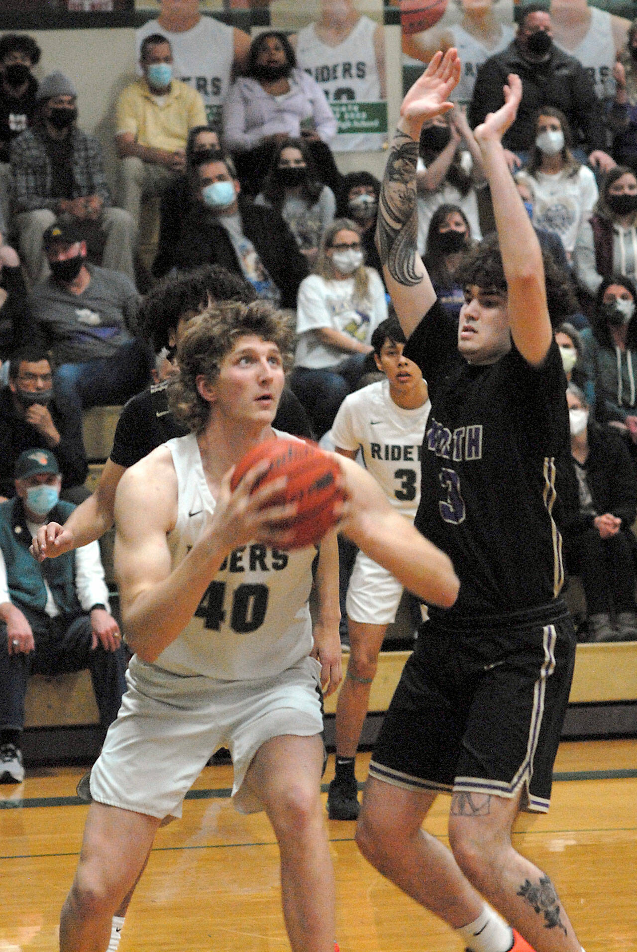 Port Angeles’ John Vaara, left, looks for the hoop as North Kitsap’s Aiden Olmstead defends the lane on Thursday night in Port Angeles. (Keith Thorpe/Peninsula Daily News)