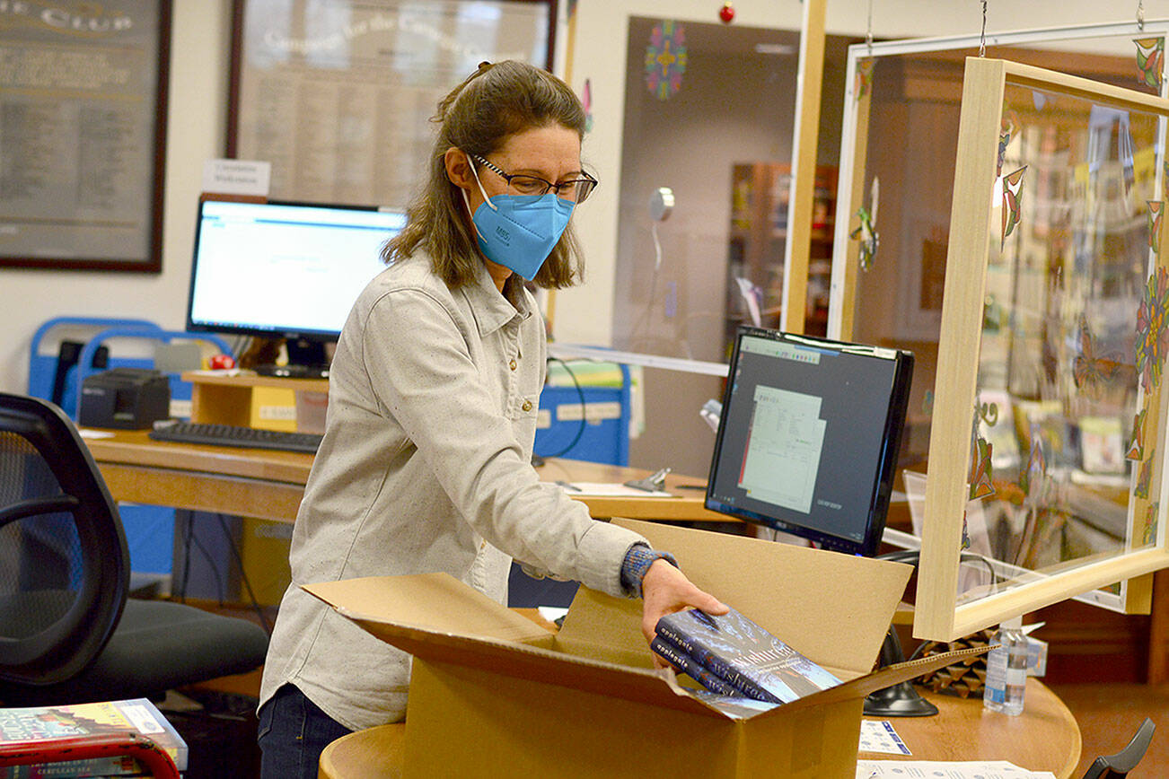 Library Assistant Nancy Grant unpacks one of the 40 boxes of books that arrived at the Port Townsend Library on Friday. The books — a novel and a children’s chapter book — are for the 2022 Community Read. (Diane Urbani de la Paz/Peninsula Daily News)