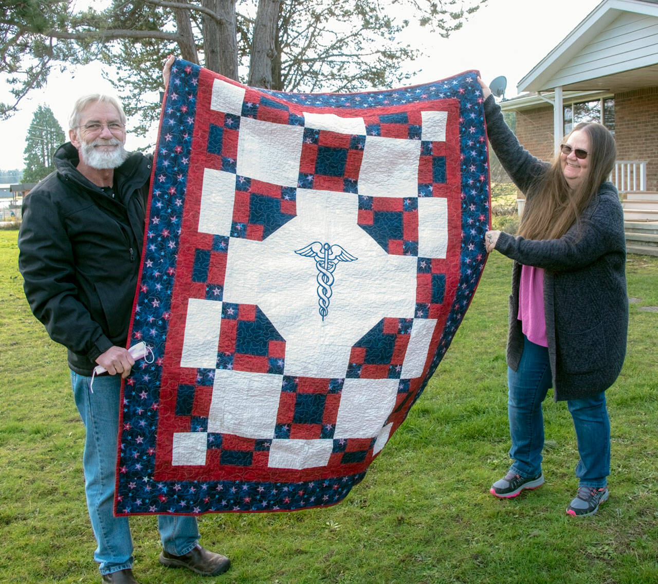 Doc and Valkyrie Ferguson hold up the Quilts of Valor quilt given to Valkyrie earlier this month. (photo by Chris Bates)