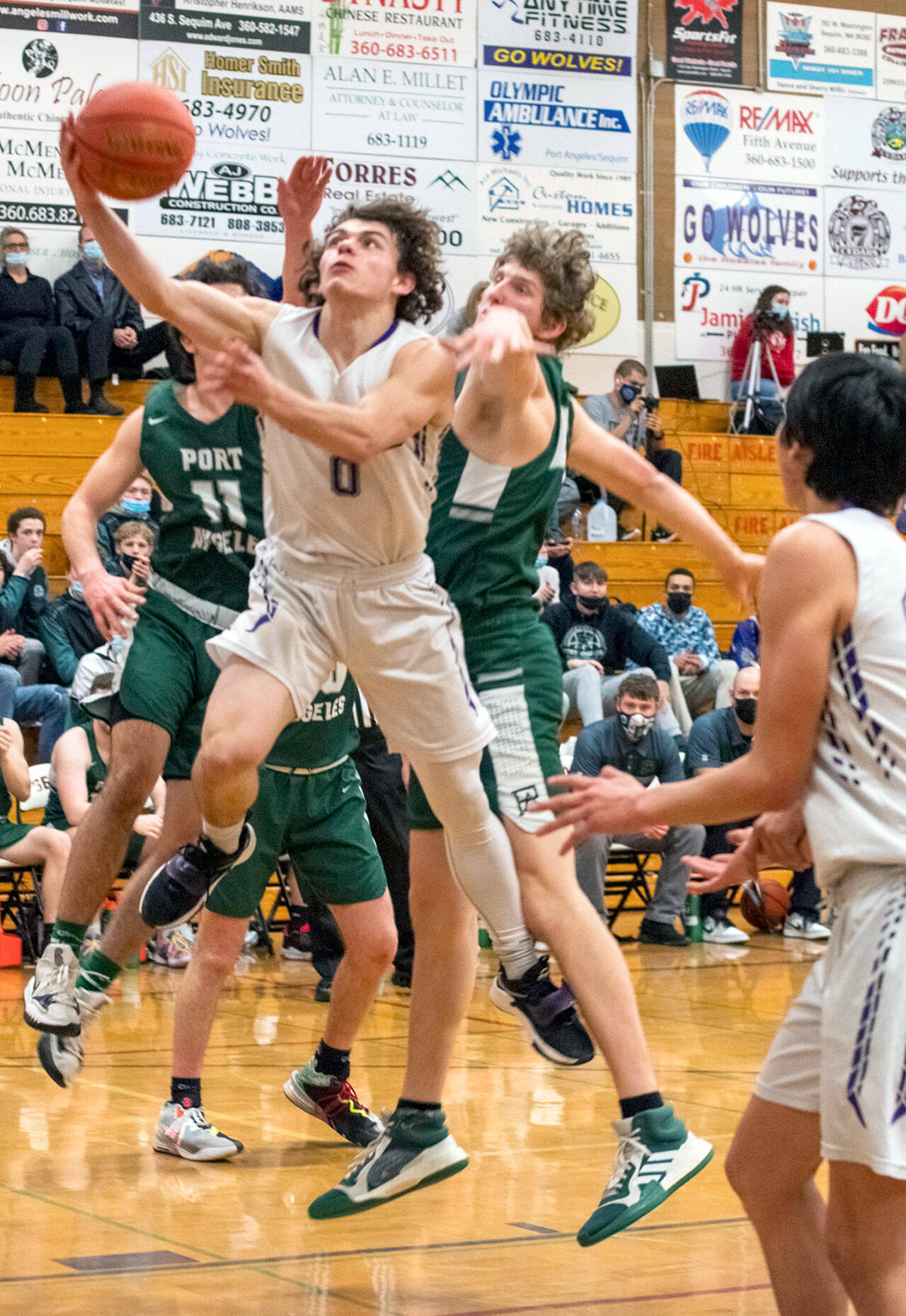 Emily Matthiessen/Olympic Peninsula News Group Sequim’s Tyler Mooney puts up a layup while defended by Port Angeles’ Xander Maestas, at left, and John Vaara during the Roughriders’ 62-49 victory Thursday.