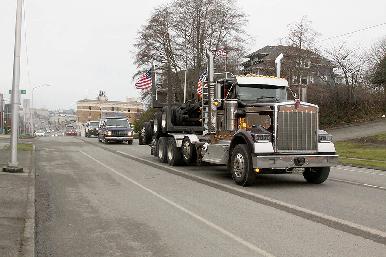 Dave Logan/for Peninsula Daily News 

Dan Conner of Port Angeles leads a convoy of more than 20 cars and trucks up First Street as they begin a drive — displaying signs, honking horns and flashing lights — from “Port to Port” from Port Angeles to Port Townsend and back on Saturday morning. The action was in support of the Canadian Freedom Convoy truckers’ protest against a vaccine mandate for truckers crossing the U.S,-Canada border implemented by Prime Minister Justin Trudeau’s government earlier this month. Saturday’s Olympic Peninsula convoy was organized through Facebook postings. Participants decorated their cars and trucks in the Clallam County Courthouse parking lot in Port Angeles before moving out.