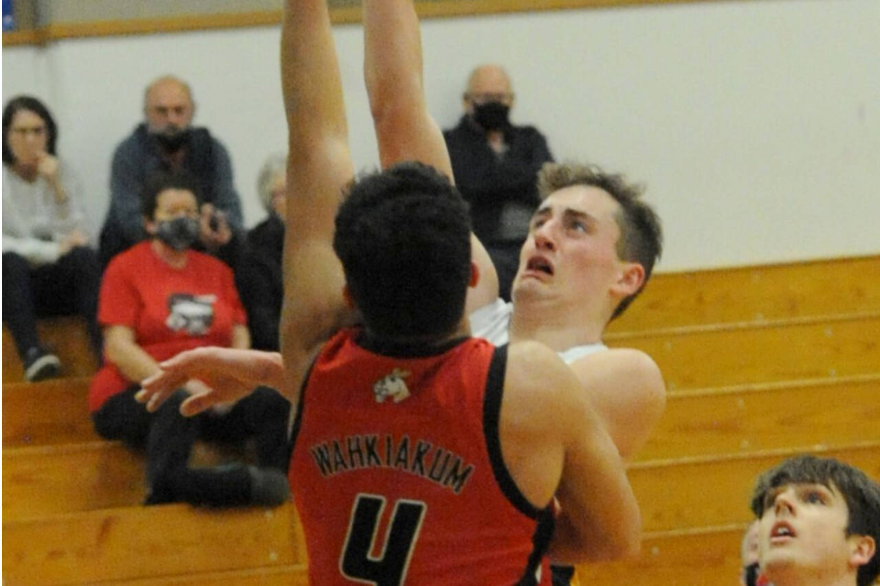 Riley Pursley shoots over Wahkiakum's Dominic Curl (4) on the court at Rochester. Rochester won 65-50, edning the Spartans' season. (Lonnie Archibald/for Peninsula Daily News)