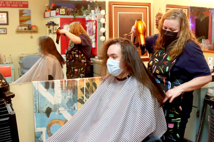 Barber Beckie Tunstall cut some 14 inches of Liam Getzin’s hair during a lengthy appointment on Feb. 18. Getzin, a Port Angeles High School senior, later donated his locks to Wigs for Kids, an organization that gives wigs to children suffering health crises. (Dave Logan/For Peninsula Daily News)