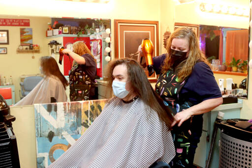 Barber Beckie Tunstall cut some 14 inches of Liam Getzin’s hair during a lengthy appointment on Feb. 18. Getzin, a Port Angeles High School senior, later donated his locks to Wigs for Kids, an organization that gives wigs to children suffering health crises. (Dave Logan/For Peninsula Daily News)