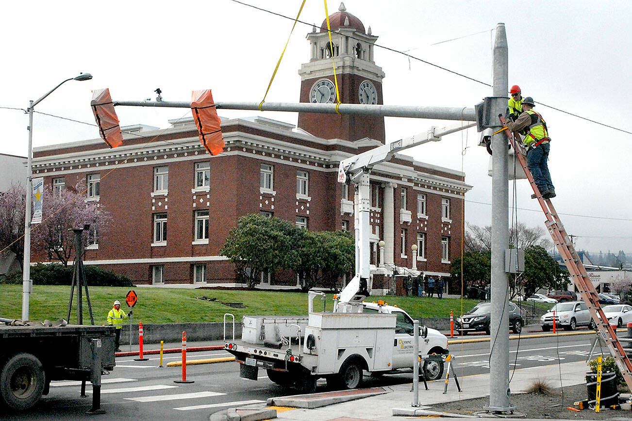 A construction crew installs a new traffic light at the corner of Lincoln and Third streets on Tuesday as a traffic improvement project along South Lincoln Street resumes. The project, which includes traffic dividers, lane revisions, sidewalks and crosswalks, began in 2021 and is expected to now add a traffic light and pedestrian crossing flashing light, with work through mid-April. Motorists can expect periodic detours and traffic delays during construction. (Keith Thorpe/Peninsula Daily News)