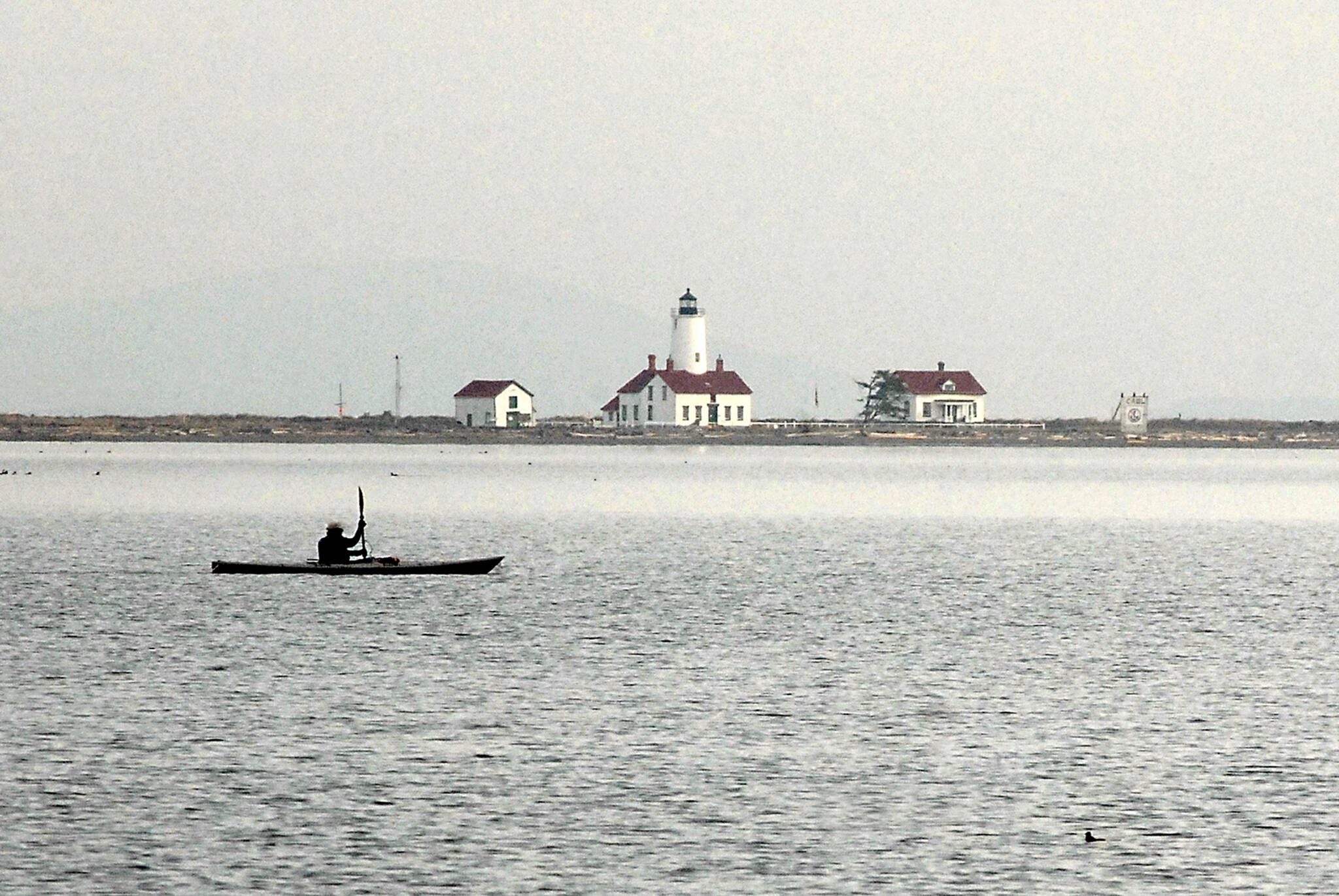 Ken Lincoln of Port Townsend kayaks across Dungeness Bay against a backdrop of the New Dungeness Lighthouse on Saturday north of Sequim. Lincoln said he was paddling out from Cline Spit to meet a group of other kayakers who were putting in at Port Williams. (Keith Thorpe/Peninsula Daily News)