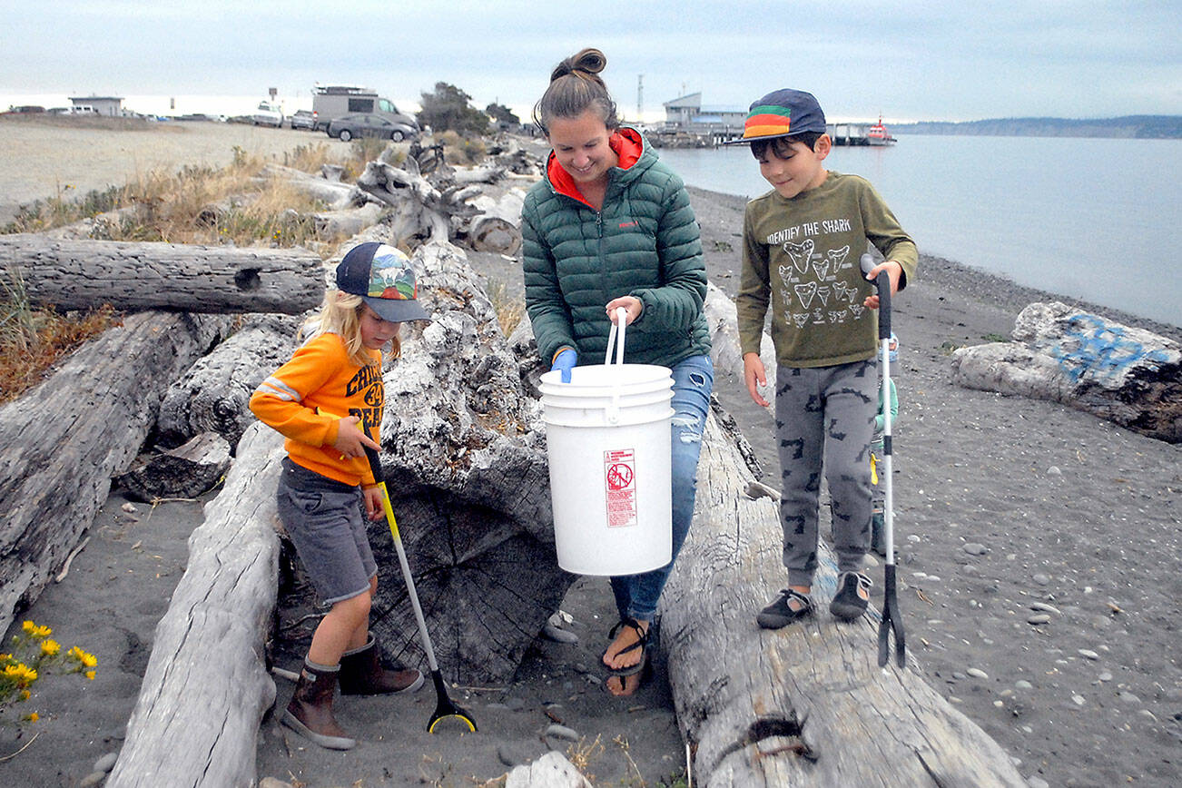 Keith Thorpe/Peninsula Daily News
Tegan Glaude of Port Angeles, center, along with 5-year-old Wolf Schultz-Wade, left, and Odin Glaude, 6, pick up trash in the driftwood along Ediz Hook in Port Angeles as part a beach cleanup effort in 2021. The event was hosted by CoastSavers and the Olympic Peninsula Chapter of the Surfrider Foundation.