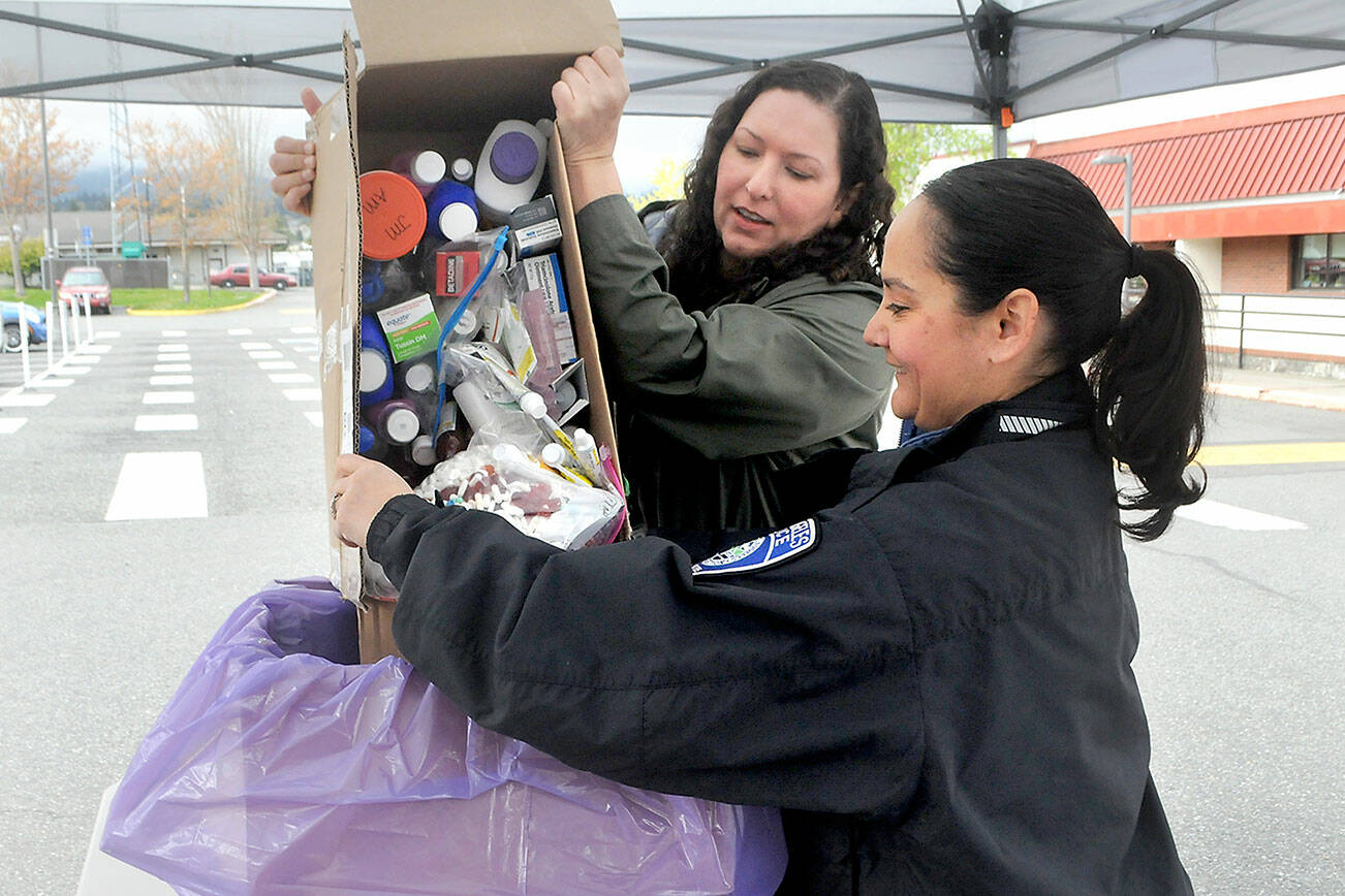 Nicole Salim, evidence manager for the Clallam County Sheriff’s Office, left, and Detective Swift Sanchez of the Port Angeles Police Department dump medicines into a collection box during National Prescription Drug Take Back Day on Saturday at a drop-off site at the Clallam County Courthouse in Port Angeles. At the event, people were allowed to anonymously bring in expired, unused and unwanted prescription drugs for safe disposal. Similar drop-off sites on the North Olympic Peninsula were set for Sequim, Quilcene and Port Hadlock. (Keith Thorpe/Peninsula Daily News)