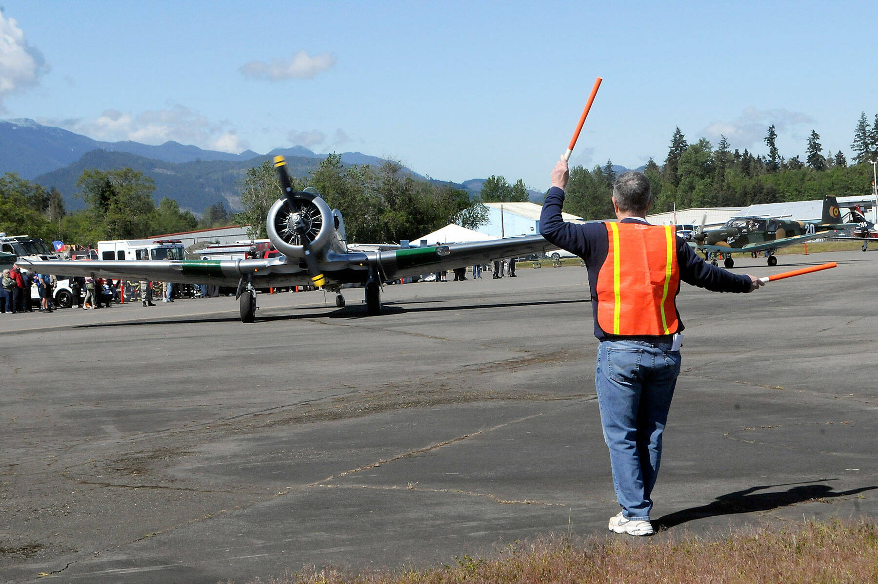 Tom Wayne Duke of Langley directs traffic as a North American SNJ-5 Texan based in Diamond Point taxies into a parking spot on Saturday at William R. Fairchild International Airport as part of Armed Forces & Public Safety Airport Appreciation Day and Fly-in. The event featured a variety of modern and vintage aircraft, flying demonstrations, public saftey displays and Young Eagles flights for children. (Keith Thorpe/Peninsula Daily News)