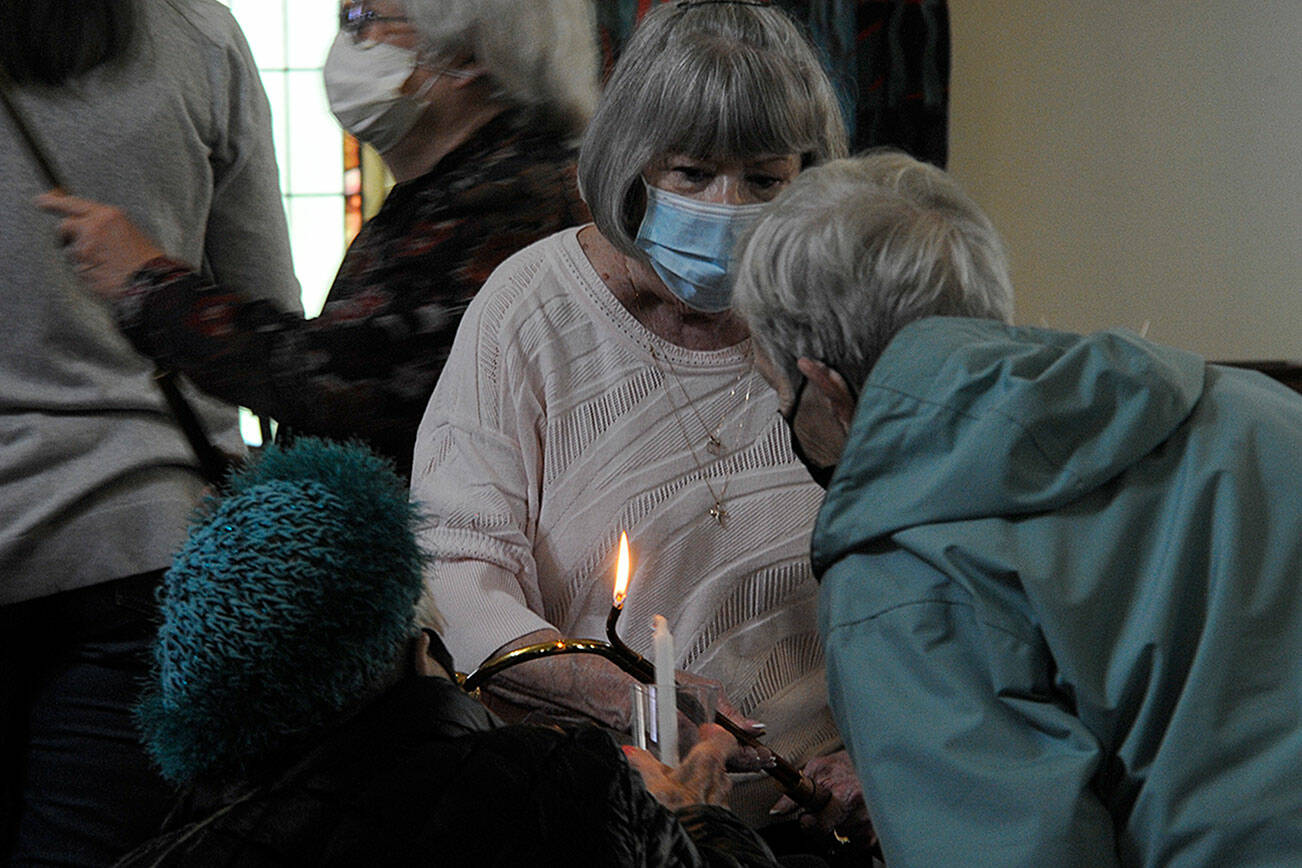 Pat Rublaitus helps light candles for a prayer service on Friday inside St. Luke’s Episcopal Church in Sequim for the victims of the Robb Elementary School shooting in Uvalde, Texas. About 40 people attended to pray and sing for the teachers and students and their families. Participants were encouraged to write prayers on cloth strips to be attached to a fence outside the church. The interfaith service was sponsored by St. Luke’s, Dungeness Valley Lutheran Church and Trinity United Methodist Church. (Matthew Nash/Olympic Peninsula News Group)