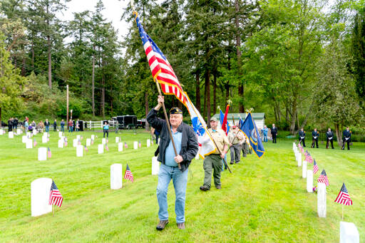 Dave Harrah, a former chaplain with American Legion Post 26 in Port Townsend, leads the color guard of scouts from Troop 1480 in Chimacum, to start the Memorial Day service at Fort Worden Military Cemetery on Monday. (Steve Mullensky/for Peninsula Daily News)