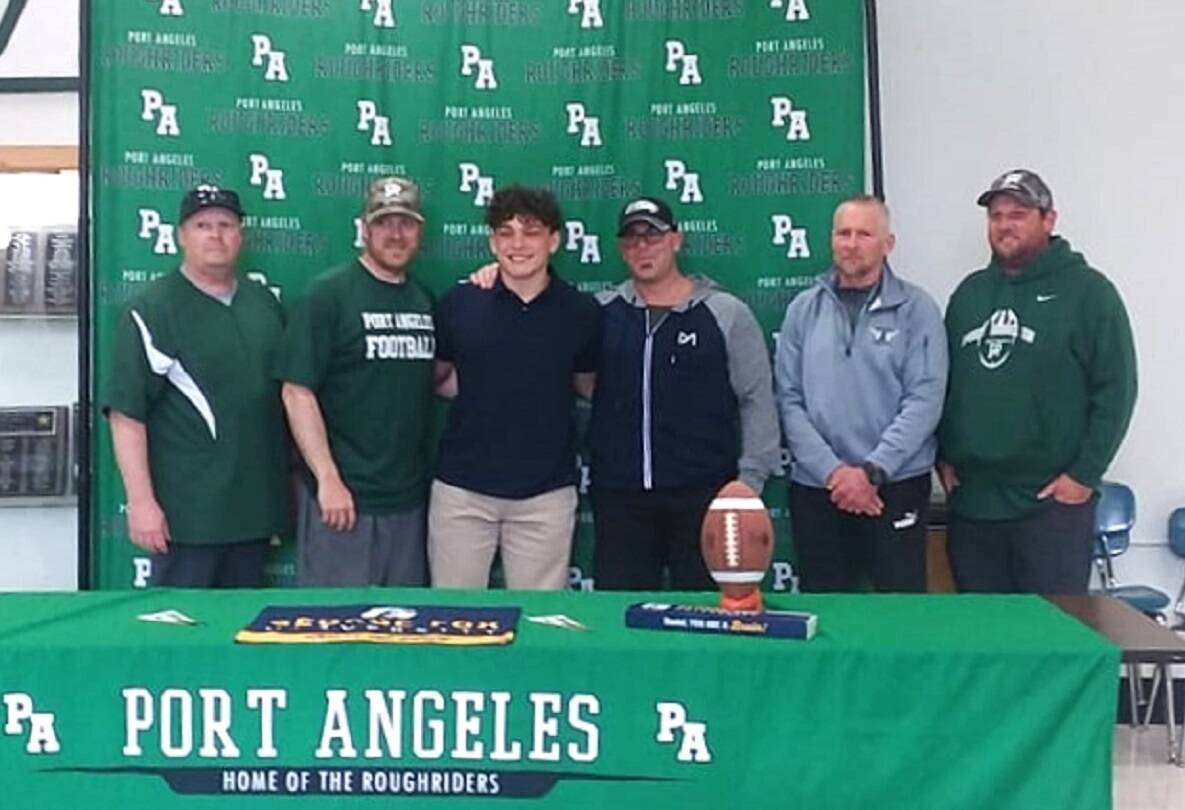 Port Angeles football player Daniel Cable signed to play with George Fox University in Newberg, Ore., on Monday. His Roughrider coaches all attended the ceremony. (Pierre LaBossiere/Peninsula Daily News)