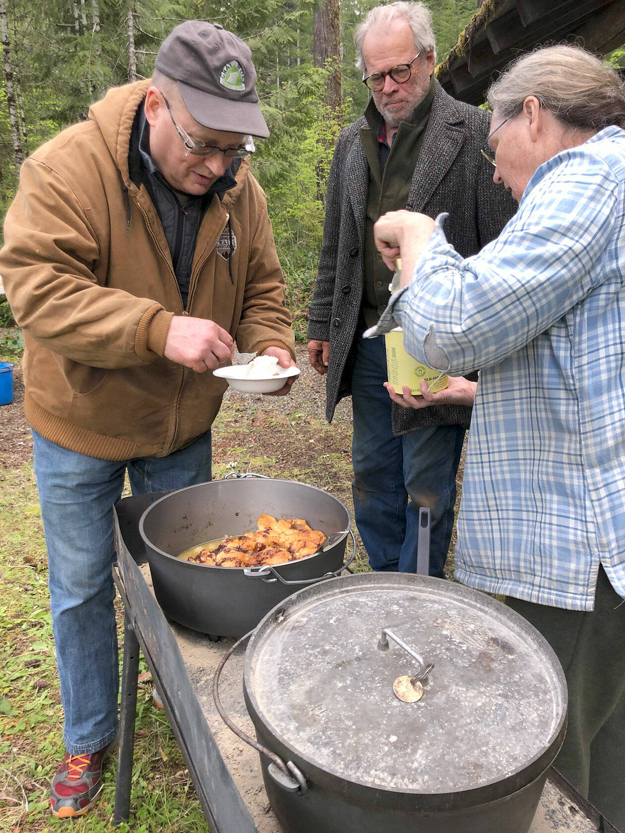 Back Country Horsemen Buckhorn Range member and “Dutch Oven Queen” Kim Merrick, right, serves dessert to Martin Knowles of the Washington Trails Association and fellow Buckhorn Range member Larry Sammons during a trail-clearing work party. (Photo courtesy Kris Lenke)