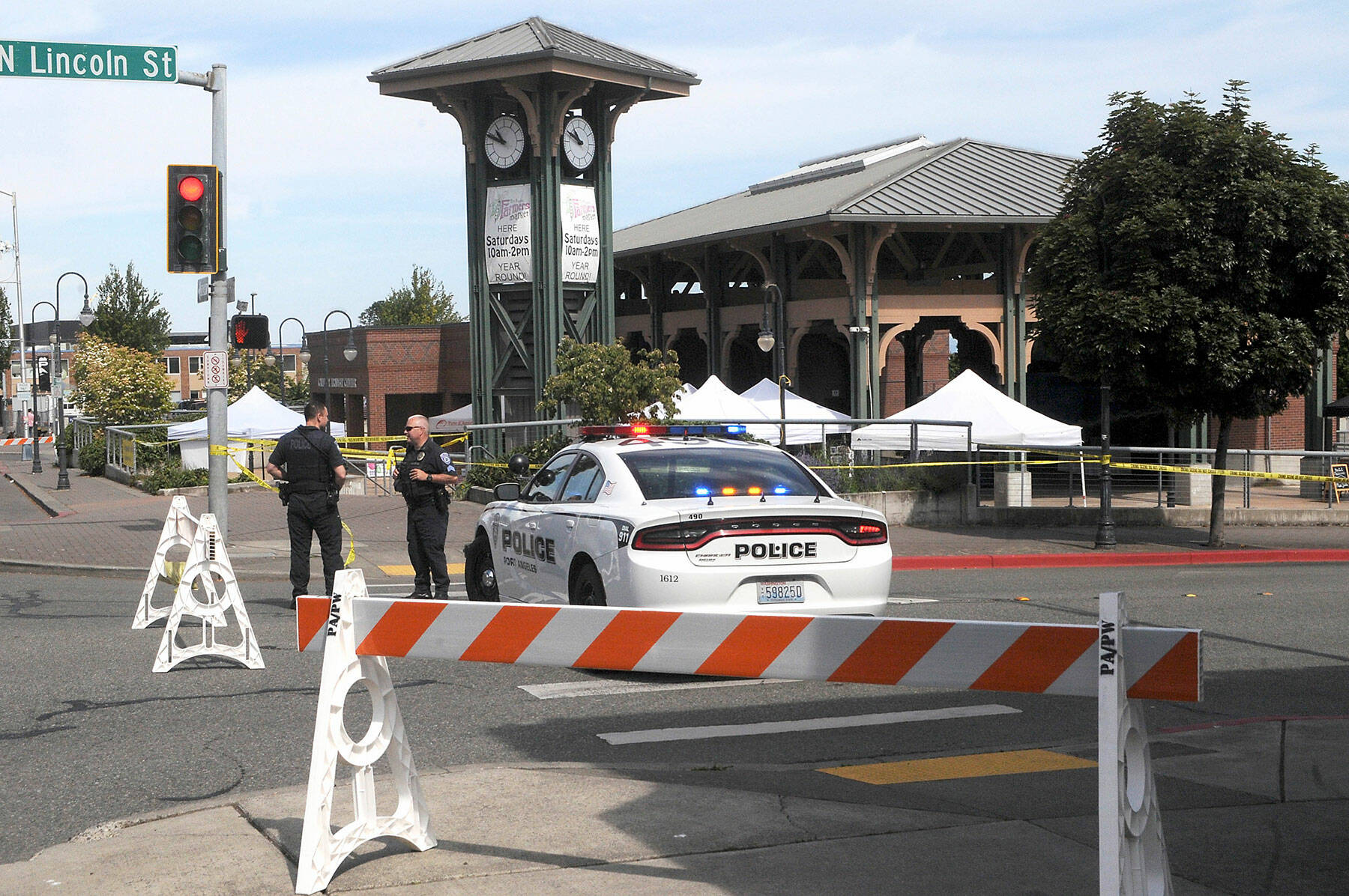 Port Angeles Police Detective Trevor Dropp, left, and Sgt. Kevin Miller keep watch at The Gateway in downtown Port Angeles after a suspicious package was found at the Port Angeles Farmers Market on Saturday morning. The market was evacuated and the 200 block of North Lincoln Street was barricaded until a Washington State Patrol bomb squad arrived from Bremerton early Saturday afternoon. (Keith Thorpe/Peninsula Daily News)