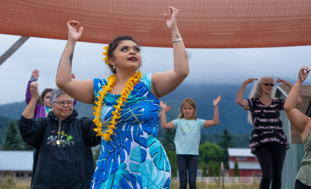 Alakaʻi in training, Casara Desiree Hemakanamaikapu`uwai Caro leads members of a Sequim audience on Saturday in a Hawaiian dance in the field behind the Sequim library. Her mother, Candace Marie Kananiokamokihana Melendez of Hālau Hula Ka Lei Mokihana I Ka Ua Noe, plays the ukulele on the stage. North Olympic Library System hosted the dance, history and language workshop as part of their summer reading program. (Emily Matthiessen/Olympic Peninsula News Group)