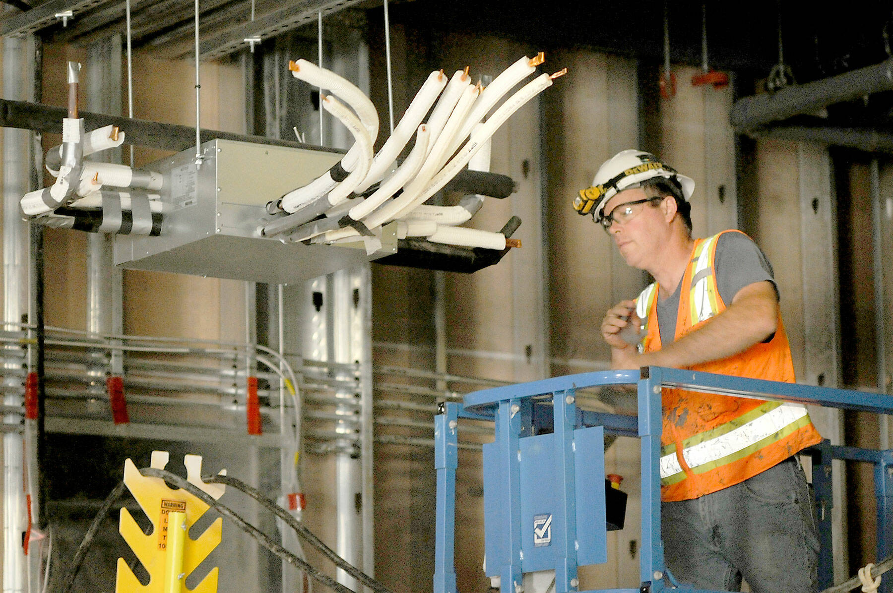 Randy Frantz of Bremerton-based Miller Sheetmetal Inc. works on overhead interior piping on Tuesday at the Field Arts & Events Hall in Port Angeles. (Keith Thorpe/Peninsula Daily News)