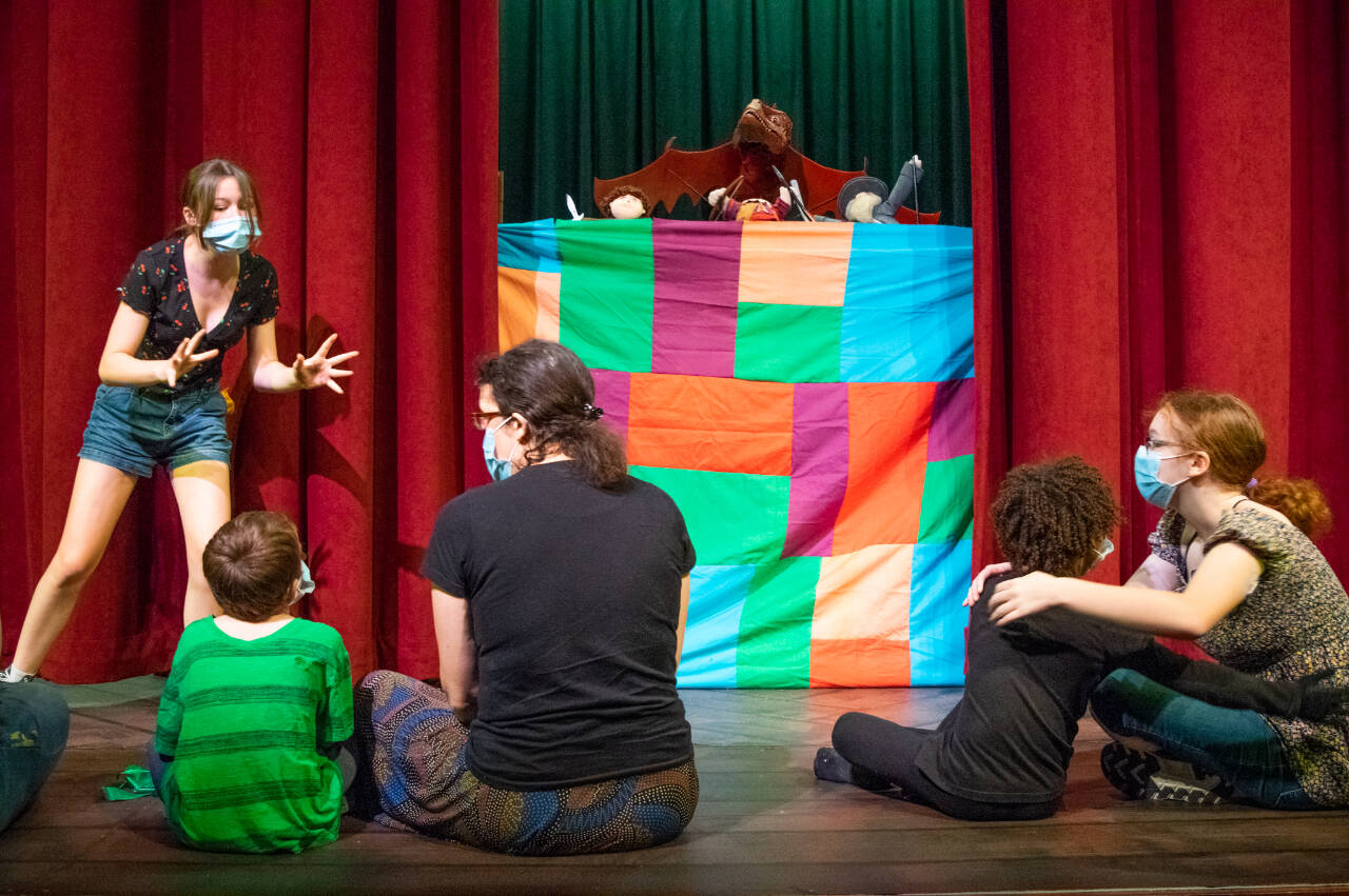 Emily Matthiessen/Olympic Peninsula News Group
Roxy Woods, a wizard/storyteller, entertains a small hobbit crowd in the first scene of Olympic Theatre Arts’ upcoming production, “The Hobbit.” The puppet show mirrors latter scenes in which giant puppets interact with the cast. From left to right: Woods, Wally McCarter (Hobbit Child), Amber McCarter (Hobbit Mother), Egan Owie (Hobbit Child), Chloe Loucks (Hobbit Mother). The hand puppets were created by Curt White.