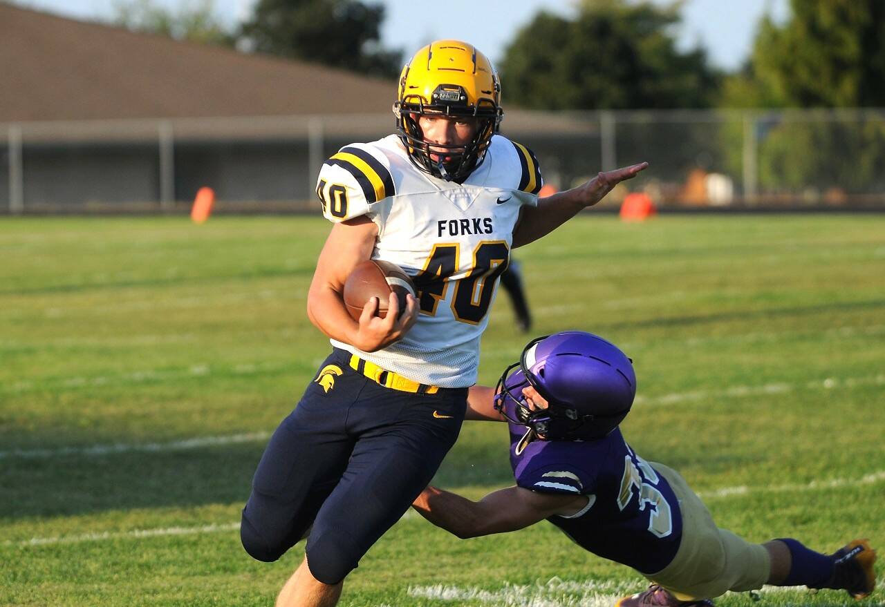 Forks running back Nate Dahlgren looks to avoid Sequim linebacker Sam Fitzgerald in the first half of Forks’ 32-14 non-league win over the Sequim Wolves on Friday night. (Michael Dashiell/Olympic Peninsula News Group)