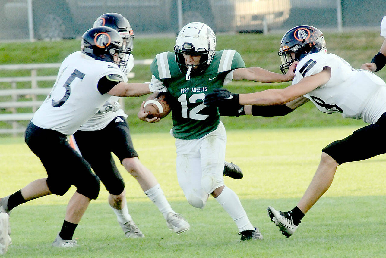 Port Angeles’ Kason Albaugh, center, tries to escape the Blaine defense of Logan Villarreal, left, and Alejandro Moser-Hernandez, right, on Friday night at Port Angeles Civic Field. (Keith Thorpe/Peninsula Daily News)