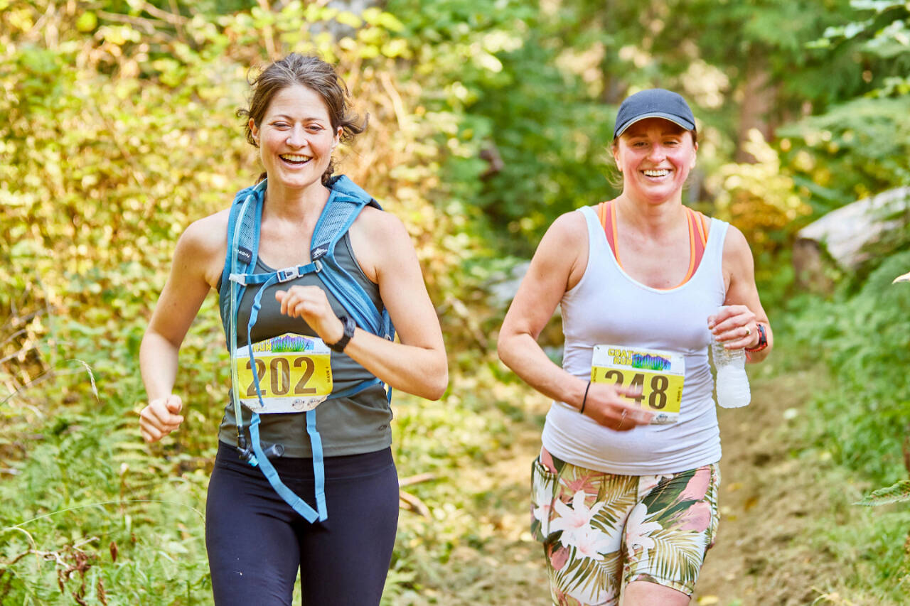 Lauren Bailey of Port Angeles, left, and Victoria Hall of Sequim run in the GOAT Run half-marathon along the Great Olympic Discovery Trail west of Port Angeles this weekend. (Matt Sagen/Cascadia Films)