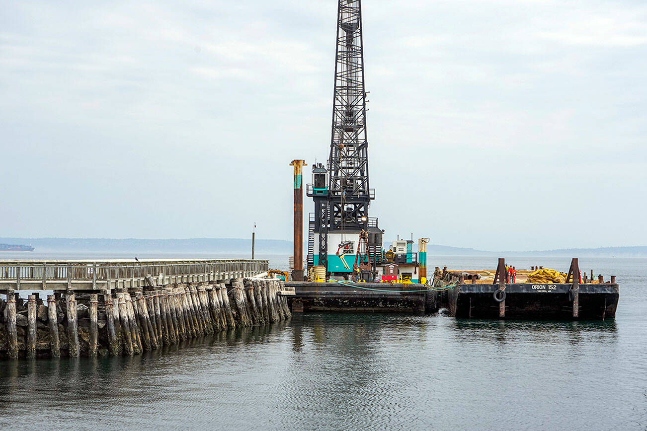 Workers prepare oil and containment boom lines on Tuesday for placing around the creosote pilings that will be removed when construction of the new entrance to Point Hudson Marina begins on Thursday. The booms will contain and extract any oil residue that might leak from the pilings. A groundbreaking ceremony is set today. (Steve Mullensky/for Peninsula Daily News)