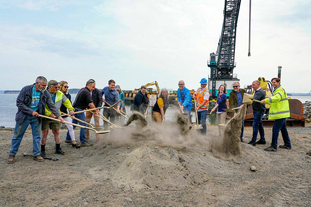 Port Townsend Mayor David Faber, sixth from the left, and other council members and port commissioners toss a ceremonial golden shovel of dirt to break ground on the Point Hudson jetty replacement project on Wednesday at the northern breakwater of the Point Hudson Marina. The marina will reopen in March 2023. After next year’s Wooden Boat Festival, the south breakwater will receive the same treatment. (Steve Mullensky/for Peninsula Daily News)