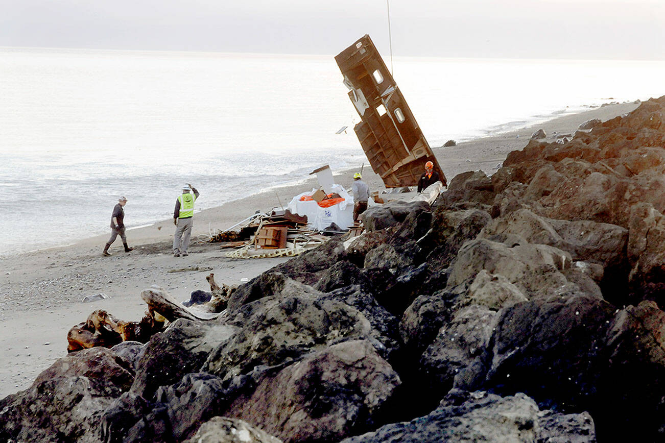 Broken wreckage of the cabin cruiser Eudora is hoisted by helicopter from the beach on Ediz Hook in Port Angeles on Wednesday as a crew hired by the state Department of Natural Resources gathers pieces of the shipwrecked vessel. (Keith Thorpe/Peninsula Daily News)