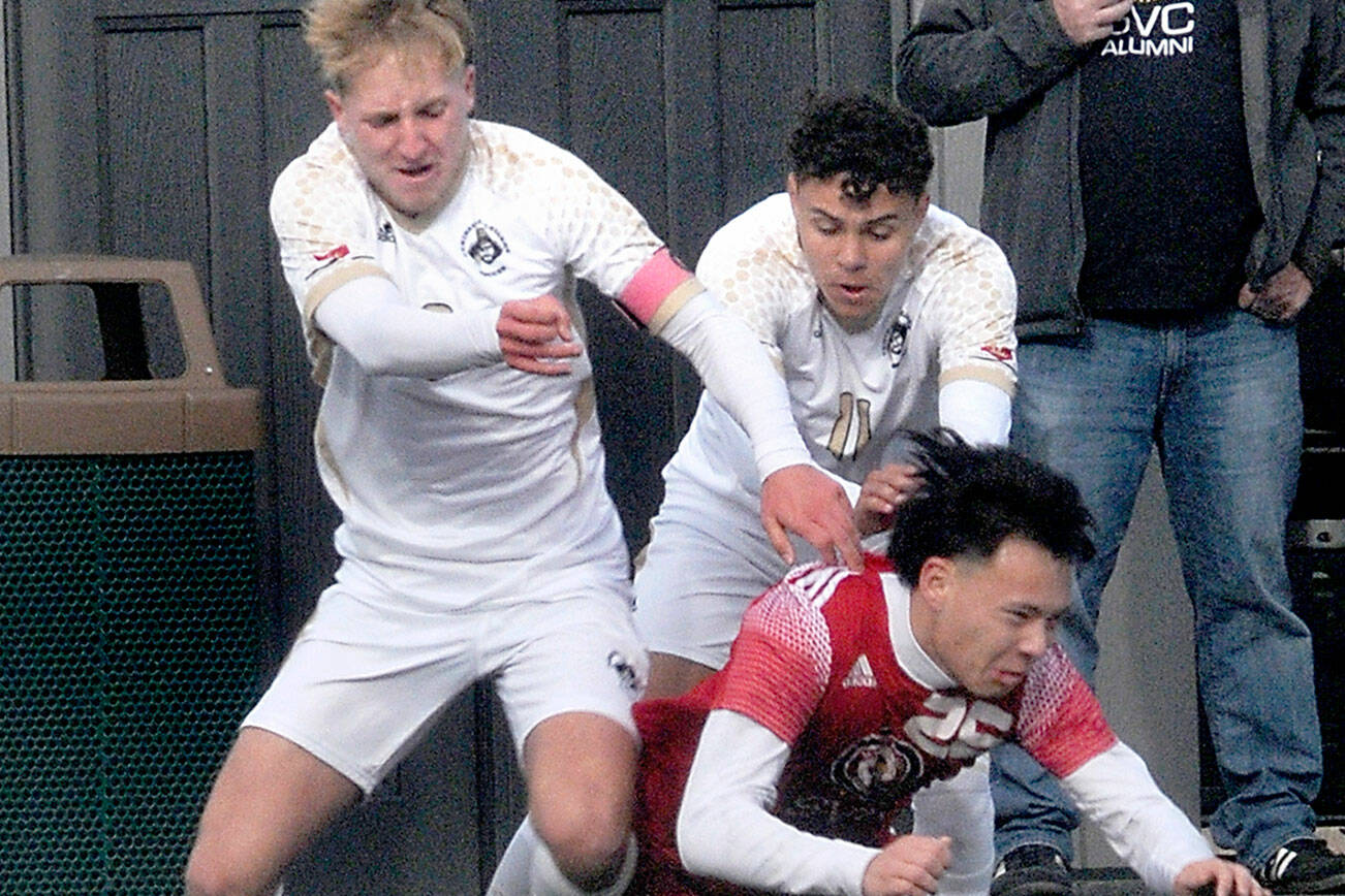 KEITH THORPE/PENINSULA DAILY NEWS
Peninsula's Tim Deser, left, and teammate Alfonso Santos de Cruz, push down Skagit Valley's Oscar Ibarra for a penalty on Saturday in Port Angeles.