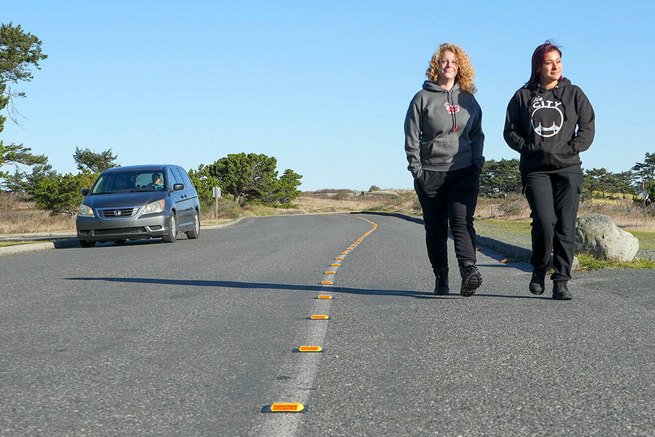 Danielle Osmum, left, and Dina Concepion, both from Las Vegas, walk safely along the newly defined pedestrian, bike and handicapped lane on Harbor Defense Way at Fort Worden State Park earlier this month. The markers were paid for by the Friends of Fort Worden by a donation of one of their members. The new installation is expected to last at least 10 years or longer. (Steve Mullensky/for Peninsula Daily News)