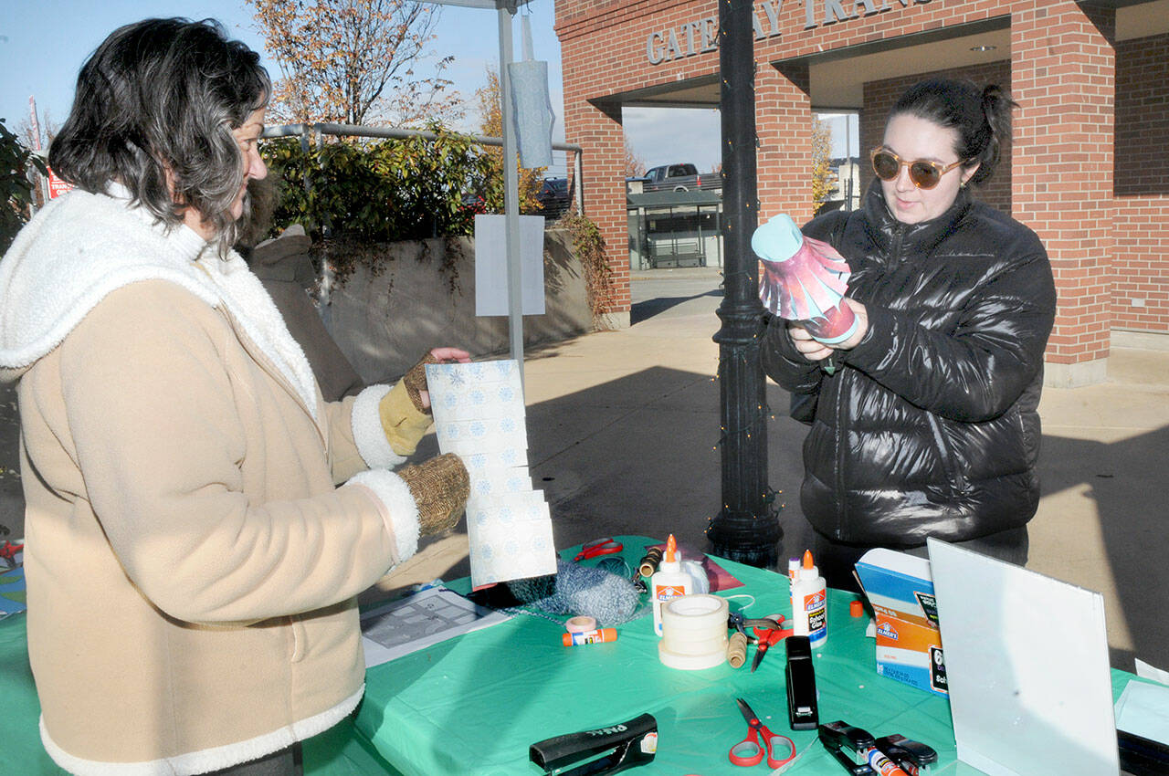 Laurel Hargis, left, and McKenzie Elliott, both of Port Angeles, assemble decorative paper lanterns on Saturday at the Port Angeles Farmers Market at The Gateway. The free activity was hosted as a public outreach event by the Juan de Fuca Foundation and the Port Angeles Fine Arts Center. Workshops are planned Tuesday and Nov. 30 before the Wintertide Festival of Lights on Dec. 10 For information, see pafac.org/wintertidefestival. (Keith Thorpe/Peninsula Daily News)