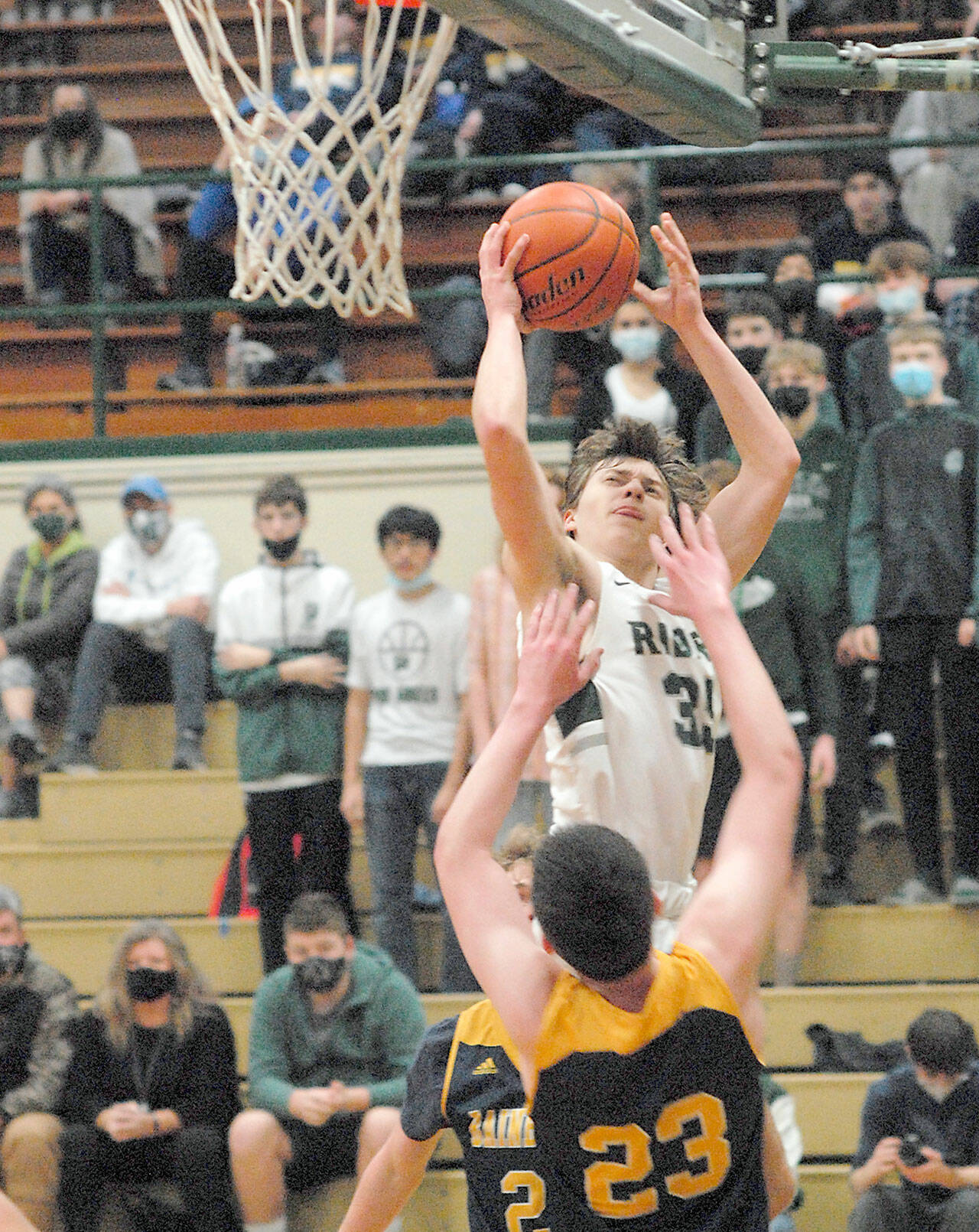 Keith Thorpe/Peninsula Daily News Port Angeles’ Parker Nickerson, top, take aim at the basket as Bainbridge Island’s James Carey defends the lane on Tuesday in Port Angeles.