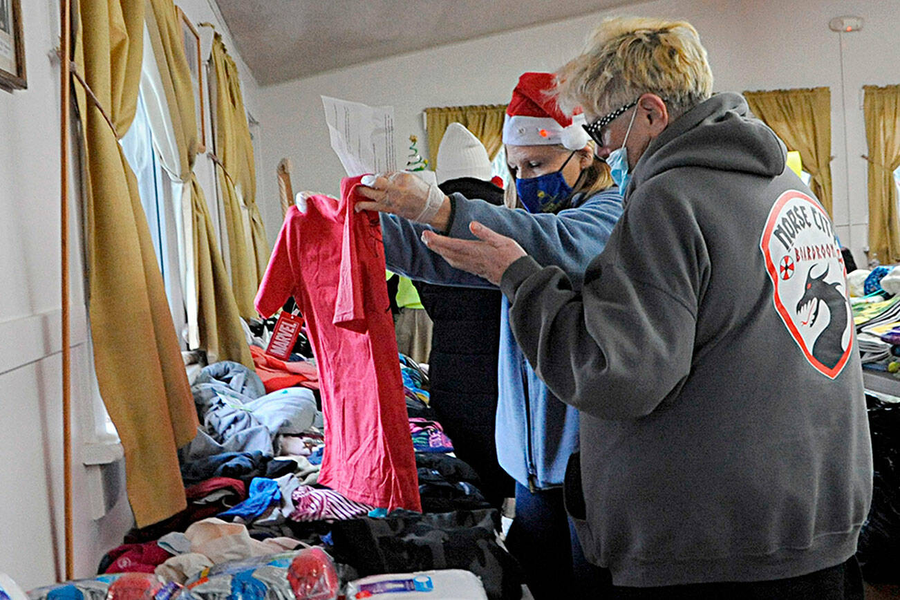 Matthew Nash/Olympic Peninsula News Group 

Kathy Joyner, co-organizer of Toys for Sequim Kids, helps Jean Ann Houk size up a T-shirt for one of her children at the 2021 event in Sequim Prairie Grange. This year’s event is set for 10 a.m. to 6 p.m. Dec. 14.