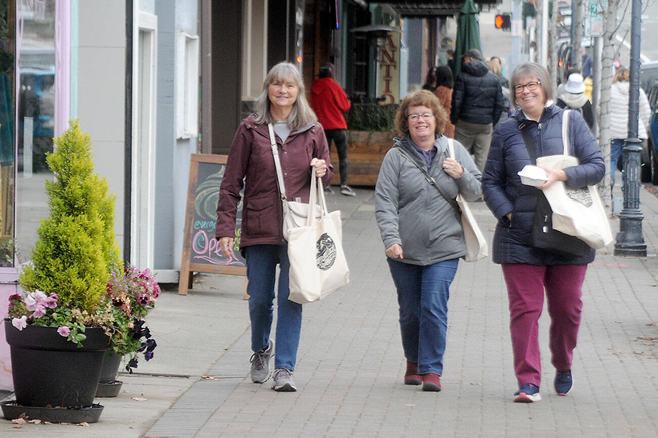 Shoppers, from left, Sue Priest, Pam Predovich and Peggy Romero, all of Port Angeles, stroll down West First Street in downtown Port Angeles searching for bargains on Small Business Saturday, a local followup to Black Friday, kicking off the holiday shopping season. Weekend shoppers were given an opportunity to purchase tote bags containing coupons for special deals from participating merchants, with proceeds from tote sales benefiting the Port Angeles Winter Ice Village. (Keith Thorpe/Peninsula Daily News)