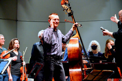 Featured soloist Stephen Schermer smiles at the audience during Saturday’s public dress rehearsal with the Port Angeles Symphony Orchestra, which brings musicians from across and beyond the North Olympic Peninsula to the Port Angeles High School Performing Arts Center. The symphony celebrated its 90th anniversary over the weekend with the world premiere of the specially commissioned Concerto for Double Bass and Orchestra by Seattle composer Sarah L. Bassingthwaighte. (Diane Urbani de la Paz for Peninsula Daily News)