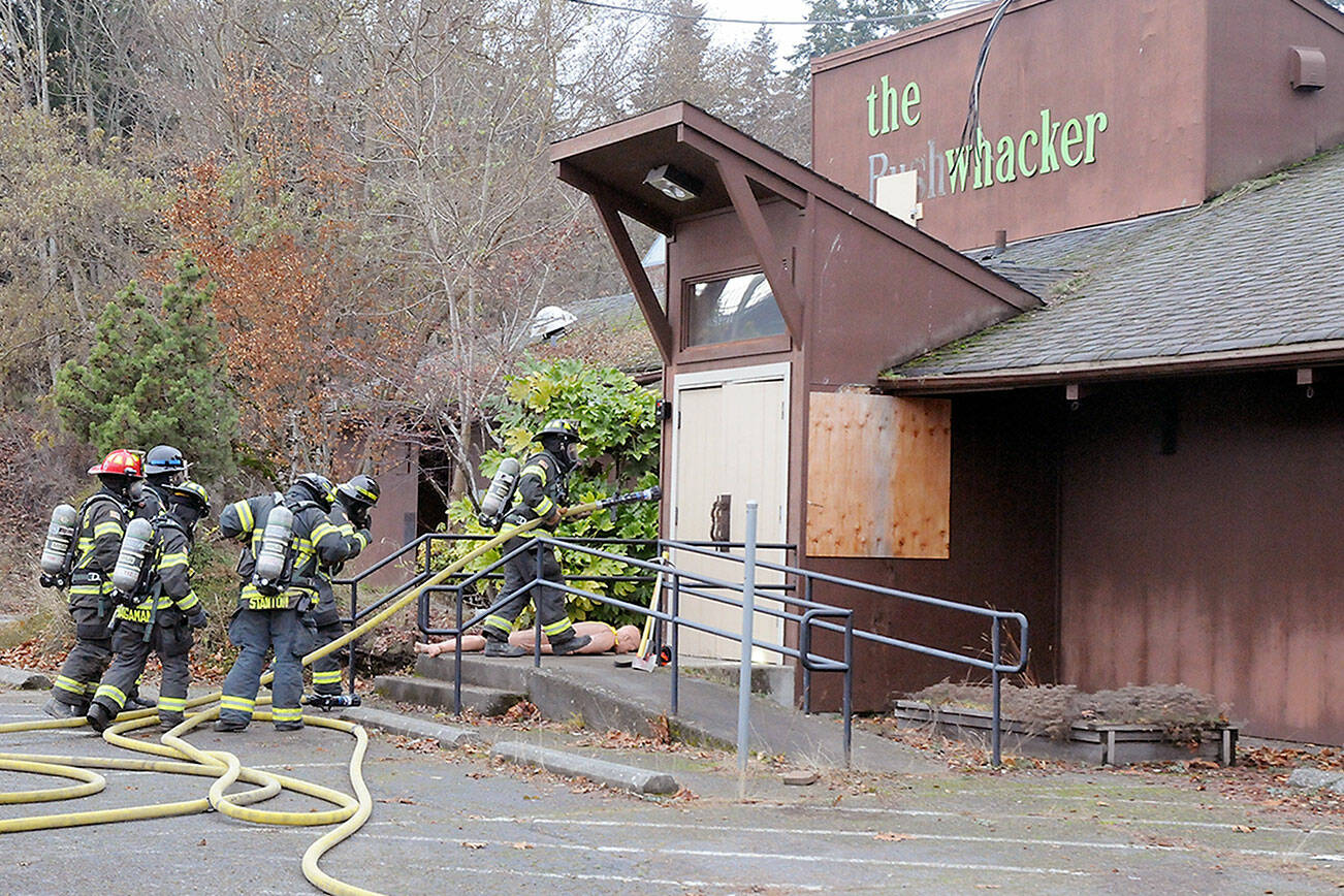 KEITH THORPE/PENINSULA DAILY NEWS
Port Angeles firefighters stage for entry into the former Bushwhacker restaurat during a fire training session on Friday. The exercise included filling the building with smoke to simulate the experience of a real fire and the use of a mannequin for rescue drills. Fire department Capt. Kelly Ziegler said the building would not be intentionally burned, but indicated that it was slated for eventual demolition.