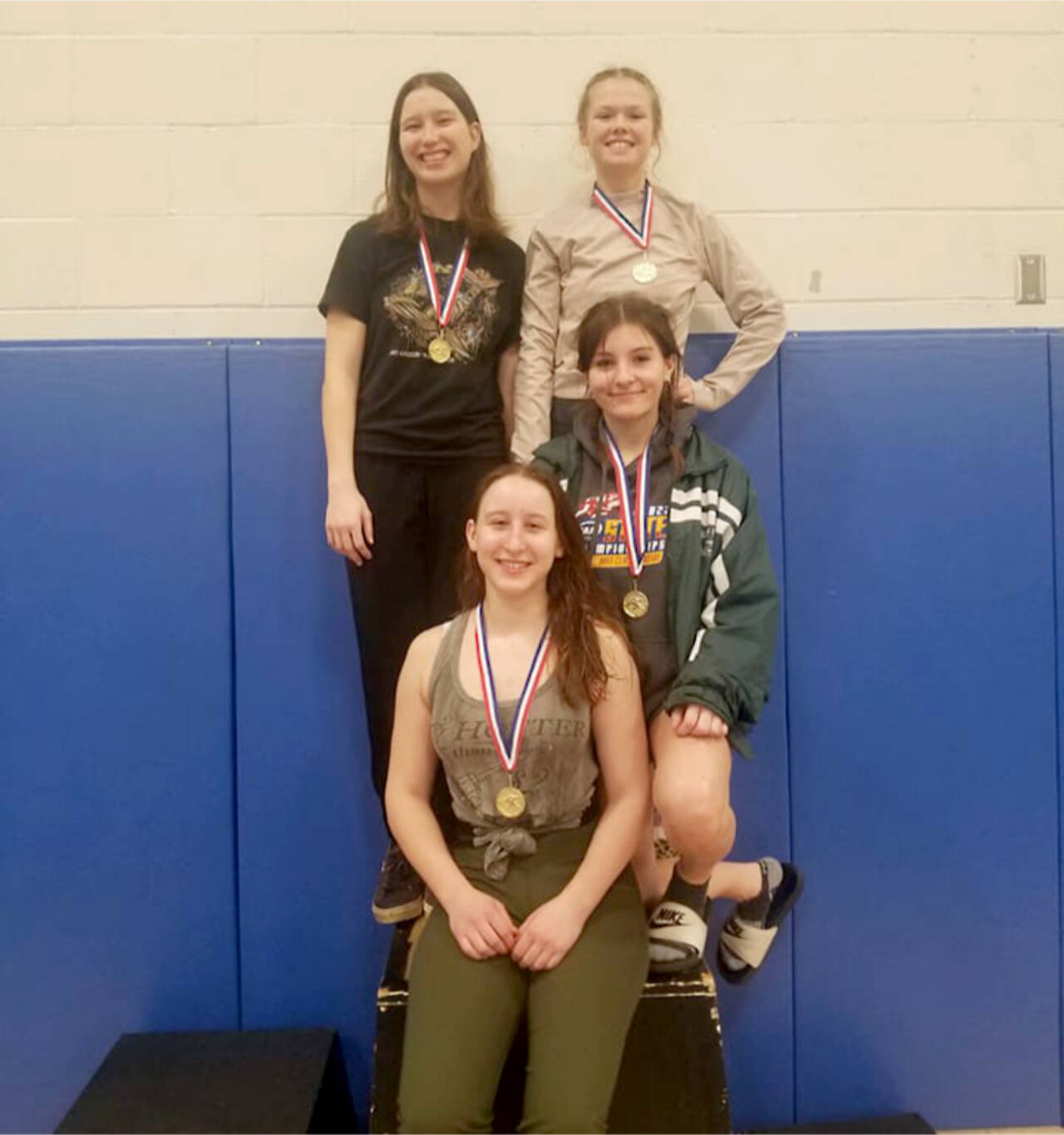 Members of the Port Angeles girls wrestling team celebrate their first-place medals from the Hawkins Memorial Tournament held in Belfair Tuesday and Wedneasday. Clockwise, from top left, are Julia Baeder, Faye Duchs, Natalie Johnson and team captain Willow Harvey. Not pictured is team member Sam Smith, who picked up a fourth-place medal. (Port Angeles wrestling)