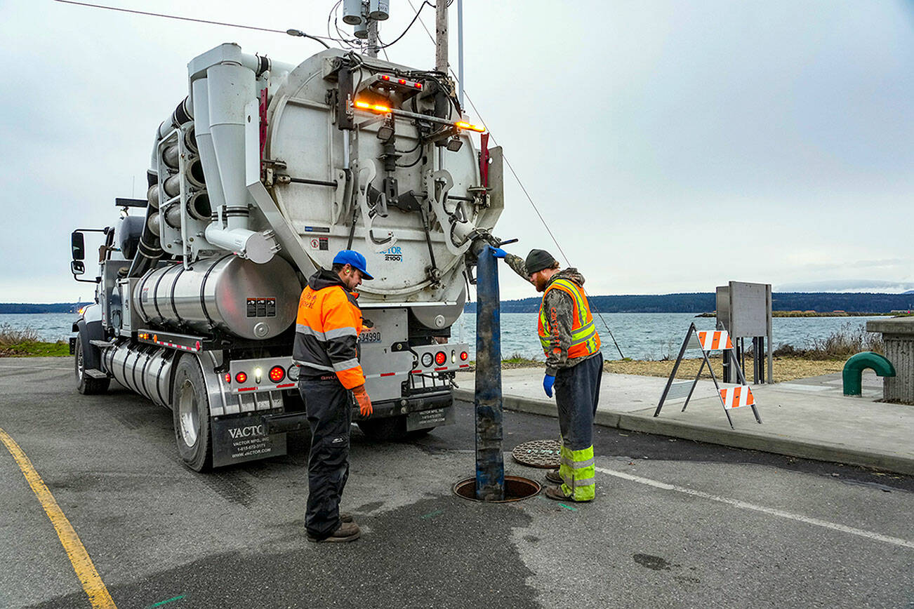 Steve Mullensky/for Peninsula Daily News

Rafe Thornton, left, and Lane Dotson, both with the City of Port Townsend Street, Sewer and Storm department vacuum sewage out of the manhole and into the truck, on Thursday, in order to facilitate repairs to the broken sewer line at Gaines and Water Streets in Port Townsend, on a newly installed sewer line damaged by recent storm and tidal activity.