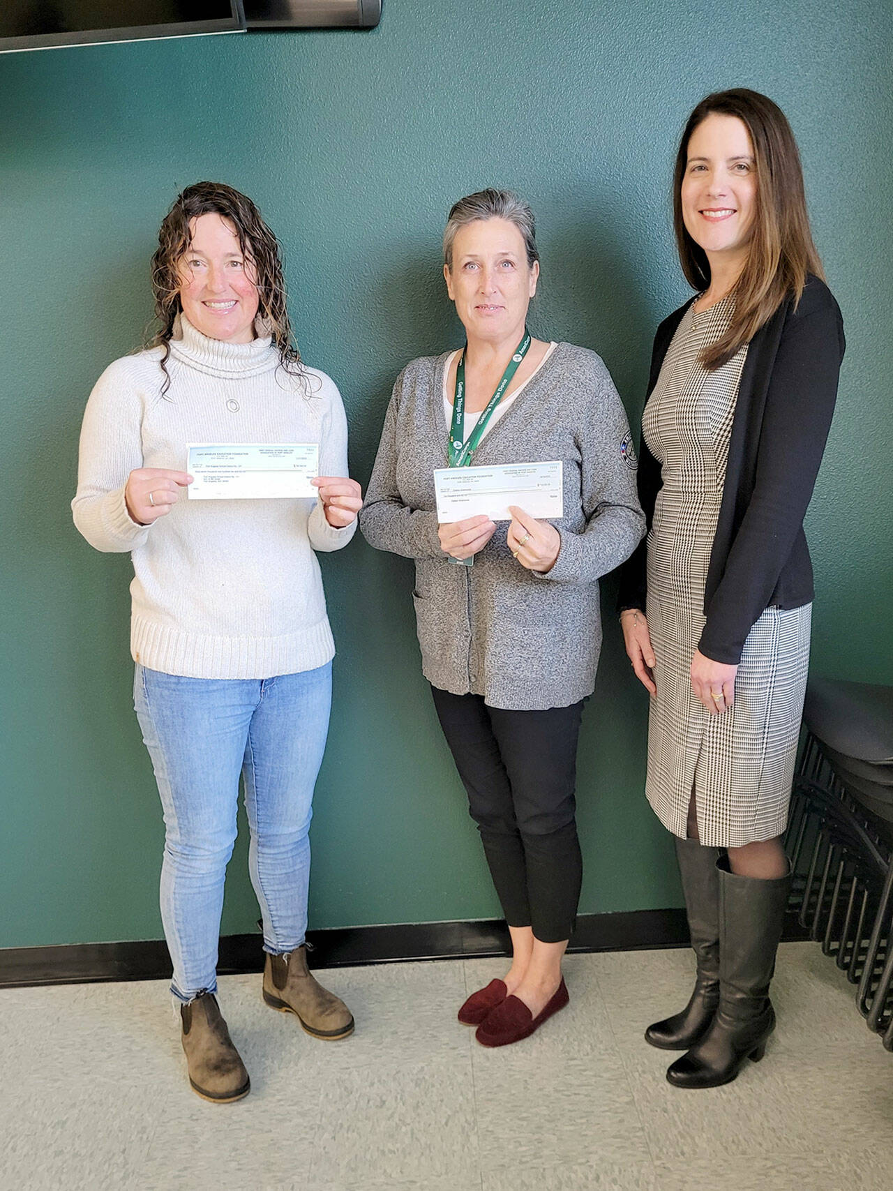 Port Angeles Education Foundation Board President Michelle Turner, on left, presents checks to Michell Gentry, AmeriCorps program director, and Kira Acker, Port Angeles School District business and operations director, on right.