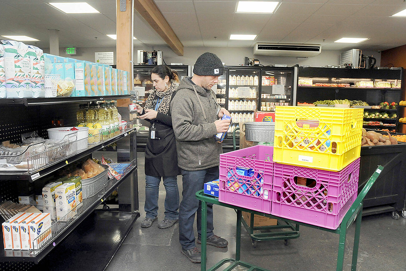 KEITH THORPE/PENINSULA DAILY NEWS
Analise Graziani, manager of The Market at the Port Angeles Food Bank, left, and Adam Frandsen, a food bank staff member with Americorps, stock shelves at The Market before opening to the public on Thursday.