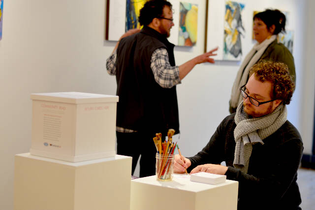 Tener Wade prepares to write a gratitude postcard at Northwind Art’s Grover Gallery in Port Townsend. Free postcards are available at the gallery and at the Port Townsend Library through this Friday as part of the Community Read program so that later this month, the postcards will become a display at the library. (Photo courtesy of Northwind Art)