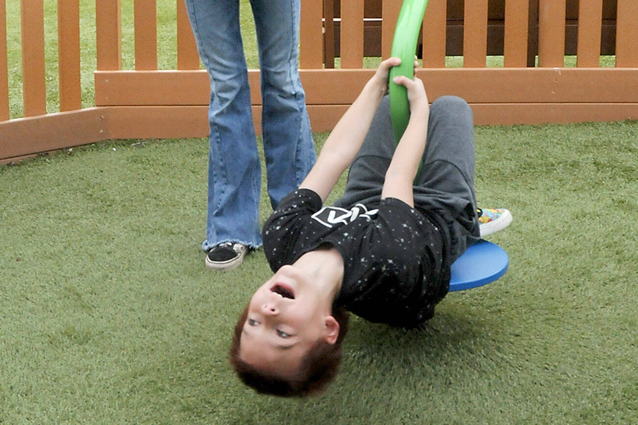 Maxamus White, 8, laughs with delight as his mother, Naomi White of Port Angeles, twirls him around on a spin toy on Saturday at the Dream Playground at Erickson Playfield in Port Angeles. The pair were enjoying a break in the weather before showers moved into the area. (Keith Thorpe/Peninsula Daily News)