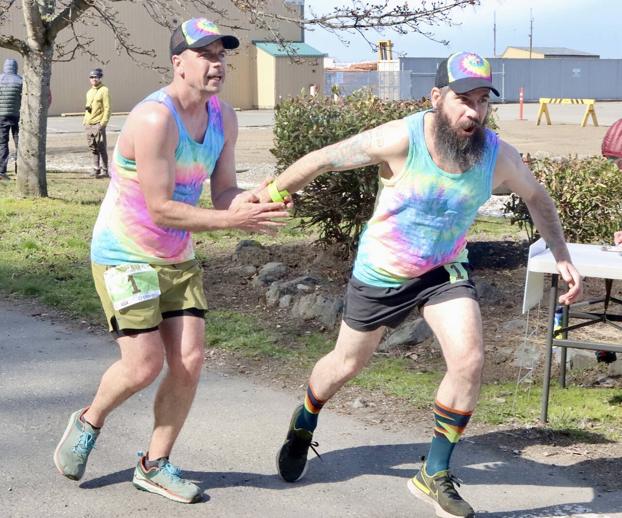 Subalpine Tees Race Team runner Chris Cummings hands the baton to brother and teammate Jon Cummings at the Port Angeles Yacht Club transfer zone during Saturday’s Frosty Moss Relay. The event that stretches from the Sol Duc Valley to Blyn featured 48 relay teams and four individuals. The Subalpine Tees finished sixth in the 80-mile race. (Dave Logan/for Peninsula Daily News)