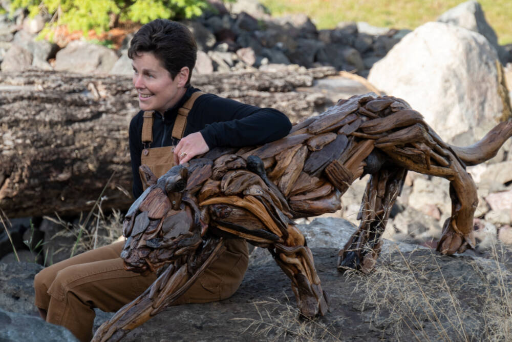 Driftwood artist Molly Omann poses with her life-sized cougar sculpture, which will be on display at Sequim Museum & Arts in April and during the First Friday Art Walk. (Molly Omann)