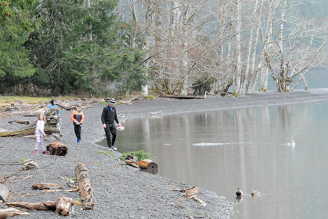 Jerry DeShazer of Ridgefield, right, along with family members, from left, Macklyn DeShazer, 6, Jace DeShazer, 11, and Jantzen DeShazer, 10, walk and skip rocks along the shore of Lake Crescent at Barnes Point in Olympic National Park. The family was on an outing to the North Olympic Peninsula with a visit to the park along the way. (Keith Thorpe/Peninsula Daily News)